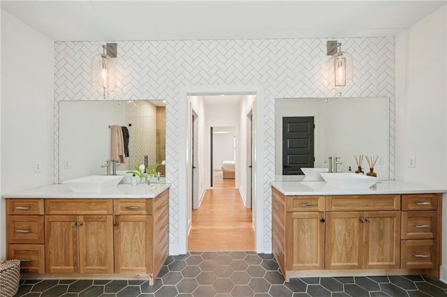 full bathroom with two vanities, a sink, and an accent wall