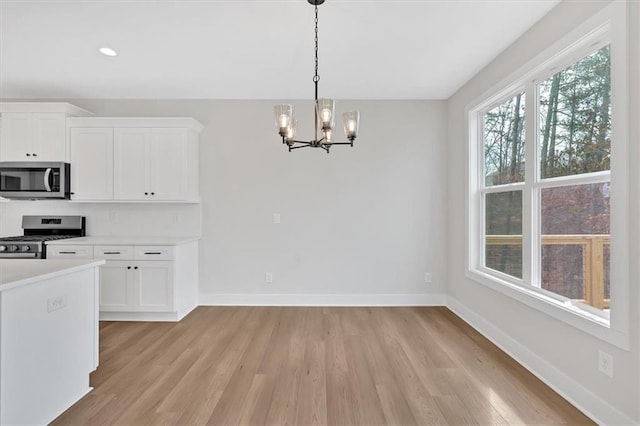 kitchen with white cabinets, decorative light fixtures, stainless steel appliances, and an inviting chandelier