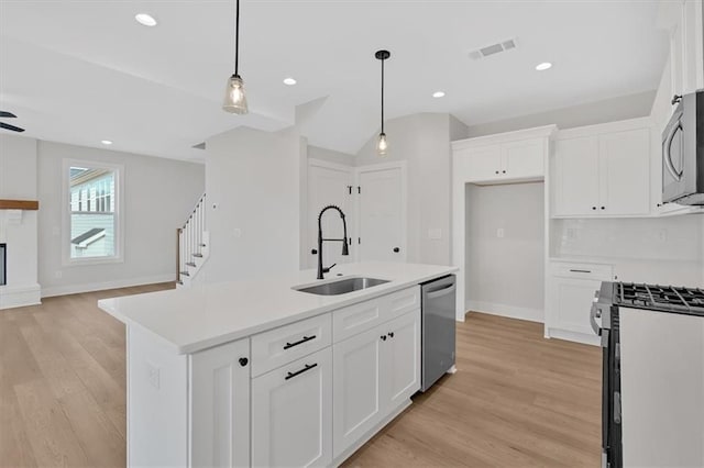 kitchen featuring white cabinetry, sink, decorative light fixtures, a center island with sink, and appliances with stainless steel finishes