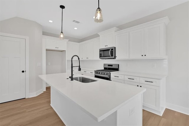 kitchen with hanging light fixtures, a kitchen island with sink, sink, and stainless steel appliances