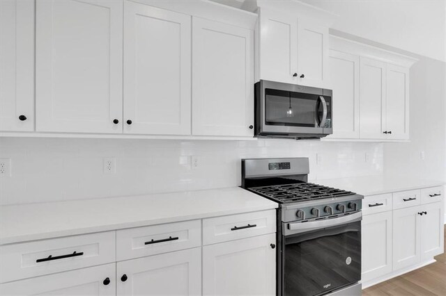 kitchen featuring stainless steel appliances, white cabinetry, tasteful backsplash, and light hardwood / wood-style floors