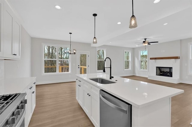 kitchen featuring pendant lighting, a kitchen island with sink, sink, white cabinetry, and stainless steel appliances