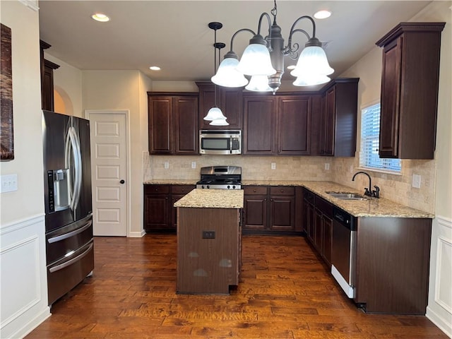 kitchen with appliances with stainless steel finishes, hanging light fixtures, a center island, dark hardwood / wood-style flooring, and sink