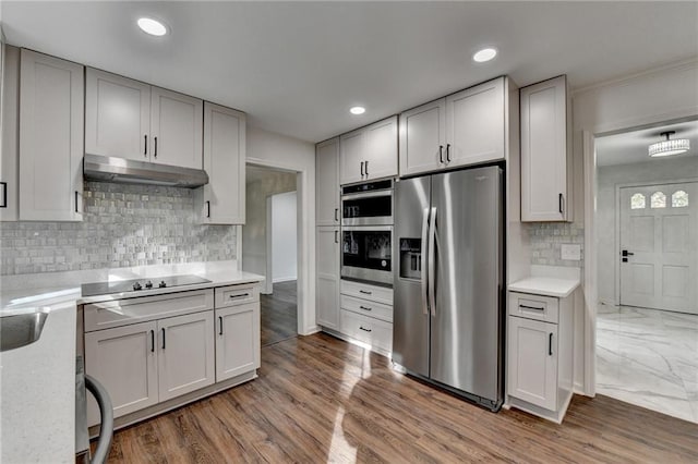 kitchen with wood-type flooring, backsplash, and appliances with stainless steel finishes