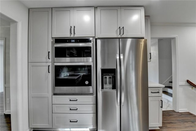 kitchen featuring ornamental molding, appliances with stainless steel finishes, and dark wood-type flooring