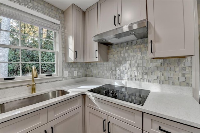 kitchen with light stone counters, sink, backsplash, and black electric cooktop