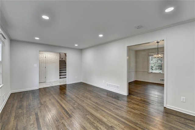 empty room featuring crown molding, a chandelier, and dark hardwood / wood-style flooring