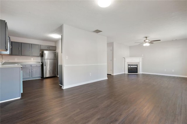 139 Palmetto St, Locust Grove, GA 30248 - unfurnished living room featuring ceiling fan, dark wood-style flooring, baseboards, and a glass covered fireplace