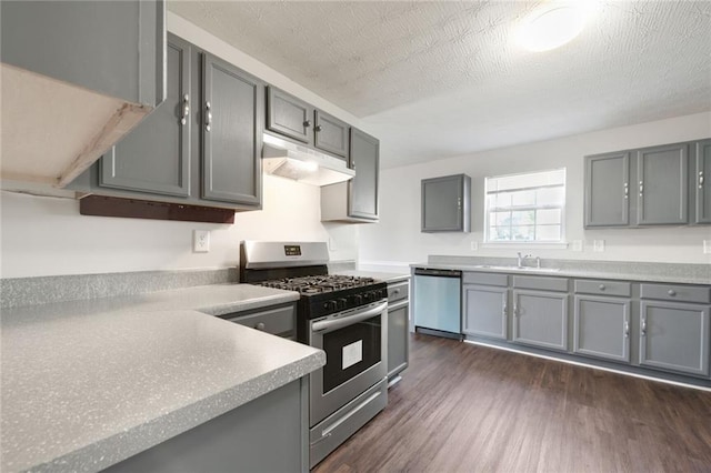 139 Palmetto St, Locust Grove, GA 30248 - kitchen featuring under cabinet range hood, appliances with stainless steel finishes, gray cabinetry, dark wood-style flooring, and a sink