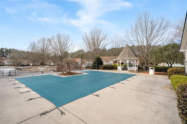 community pool with a patio area, fence, and a gazebo