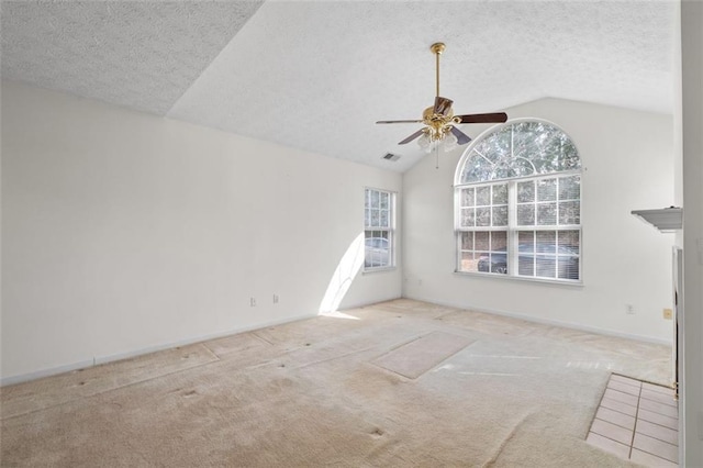 empty room featuring visible vents, light colored carpet, vaulted ceiling, and a textured ceiling