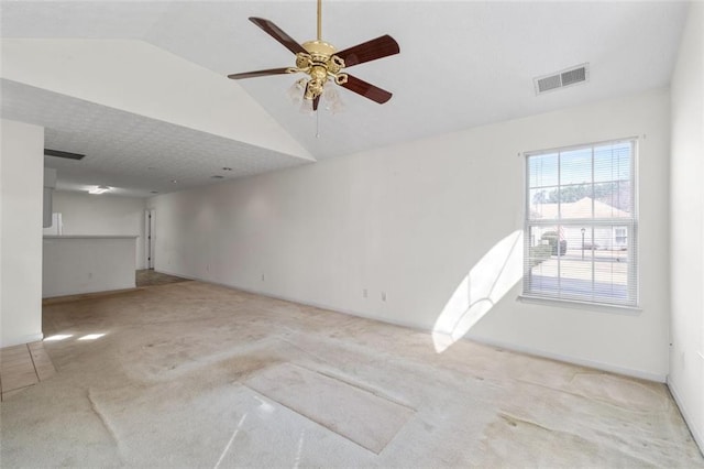 spare room featuring a ceiling fan, lofted ceiling, visible vents, and light carpet