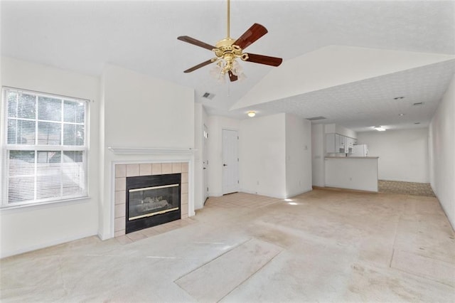 unfurnished living room with light carpet, visible vents, a ceiling fan, lofted ceiling, and a fireplace