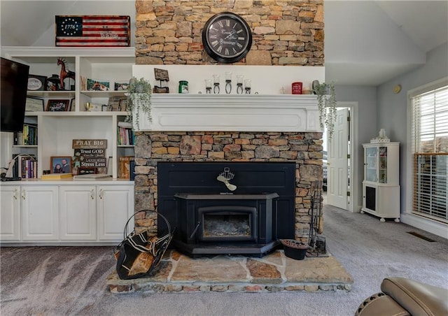 living area featuring carpet floors, a wood stove, and vaulted ceiling