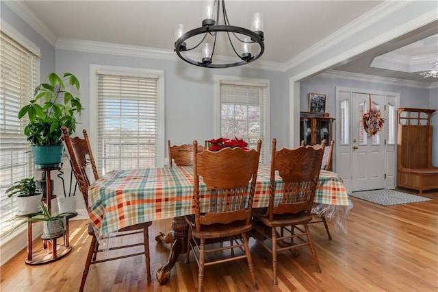 dining room featuring a chandelier, healthy amount of natural light, wood finished floors, and ornamental molding
