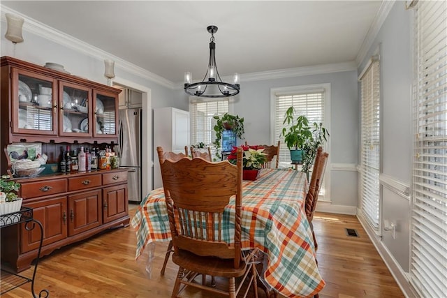 dining room with a chandelier, light wood finished floors, and ornamental molding
