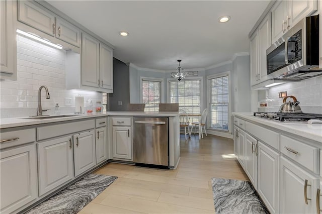 kitchen with kitchen peninsula, pendant lighting, stainless steel appliances, and tasteful backsplash