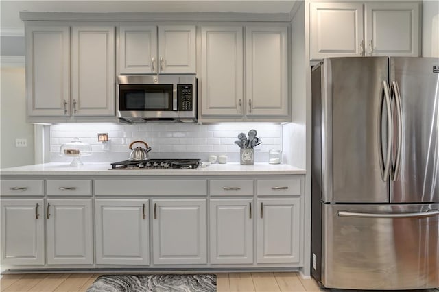 kitchen featuring stainless steel appliances, gray cabinetry, and backsplash