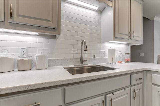 kitchen with a sink, backsplash, and light stone countertops