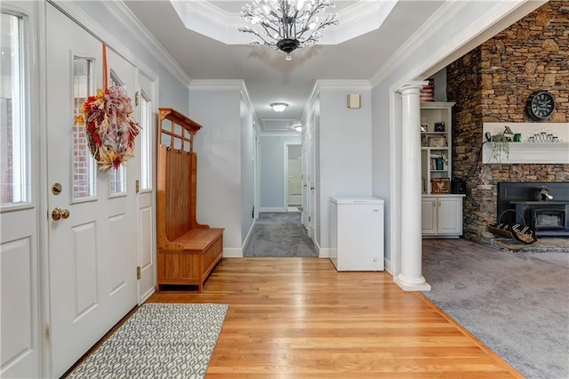 entrance foyer featuring ornamental molding, a wood stove, wood finished floors, carpet flooring, and baseboards