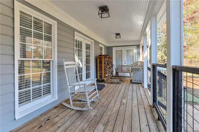 wooden terrace with french doors, covered porch, and a grill