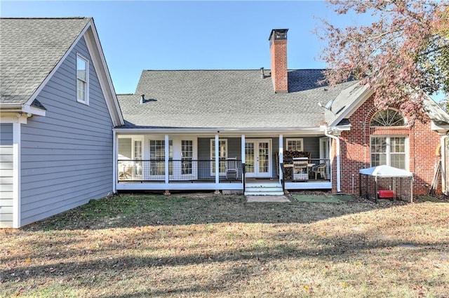 rear view of house featuring a chimney, a lawn, french doors, and roof with shingles