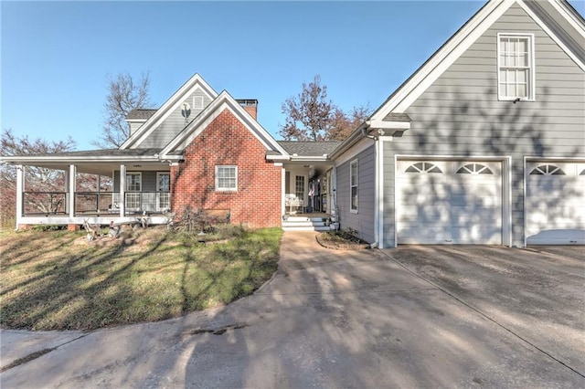 traditional-style home with covered porch, driveway, a garage, a chimney, and brick siding