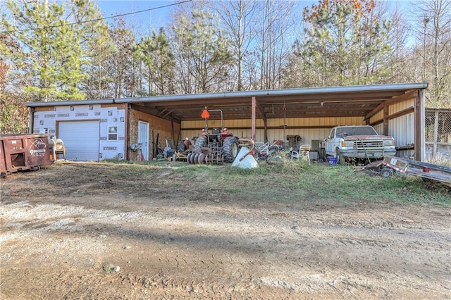 view of pole building featuring dirt driveway and a garage