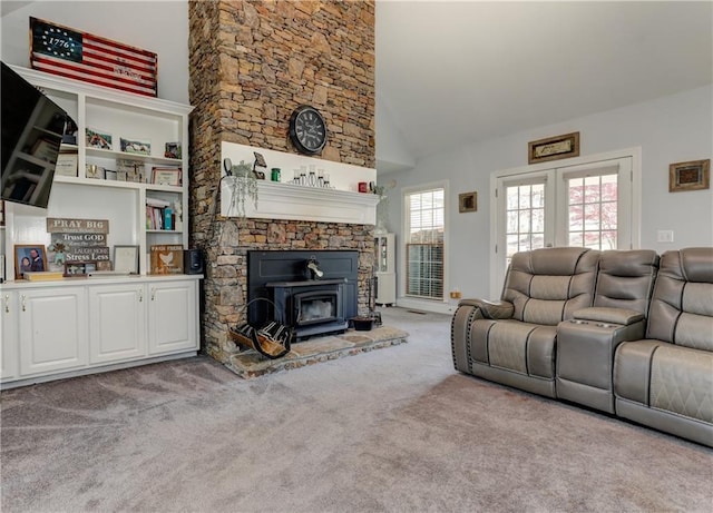 carpeted living room with a wood stove and high vaulted ceiling