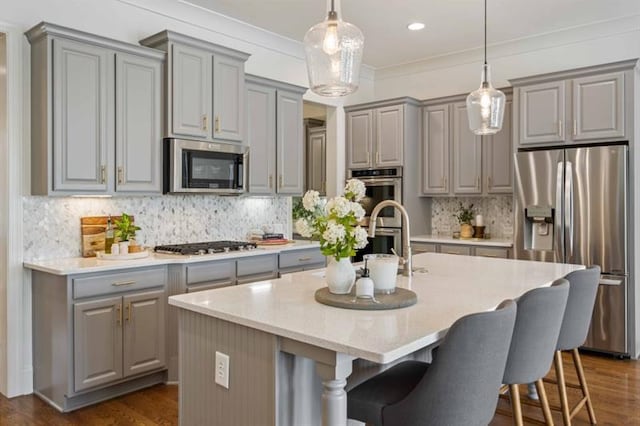 12603 Itaska Walk, Milton, GA 30004 - kitchen with gray cabinetry, stainless steel appliances, a center island with sink, a sink, and ornamental molding