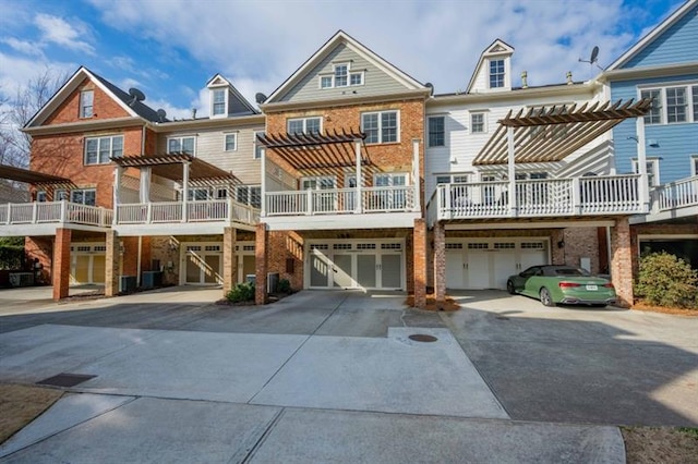 12603 Itaska Walk, Milton, GA 30004 - back of house featuring a pergola, driveway, an attached garage, and brick siding