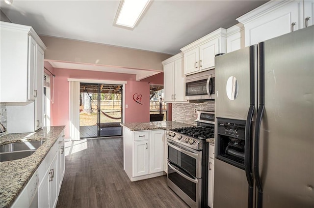 kitchen featuring appliances with stainless steel finishes, white cabinetry, light stone countertops, and sink