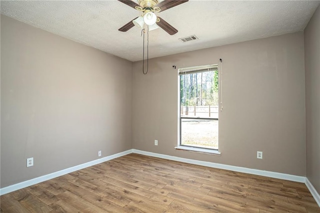 spare room featuring light wood-type flooring, ceiling fan, and a textured ceiling