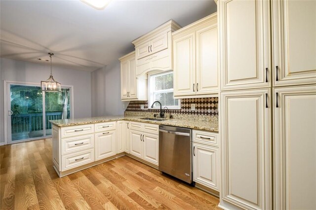 kitchen with light hardwood / wood-style floors, tasteful backsplash, kitchen peninsula, decorative light fixtures, and stainless steel dishwasher