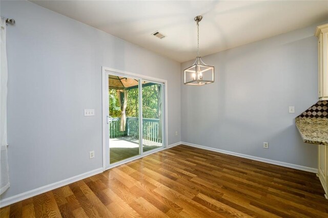 unfurnished dining area featuring wood-type flooring and a chandelier