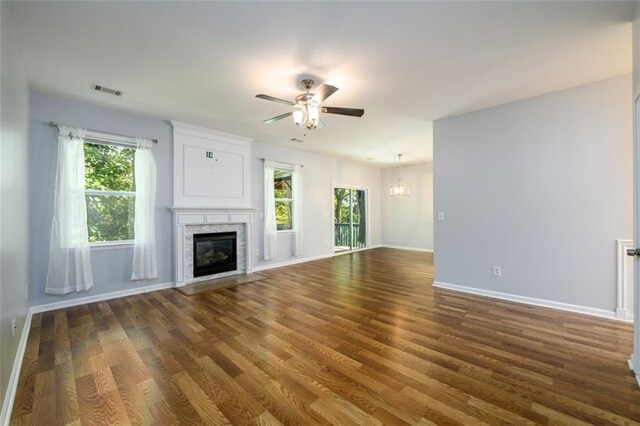 unfurnished living room featuring a healthy amount of sunlight, ceiling fan, and dark wood-type flooring