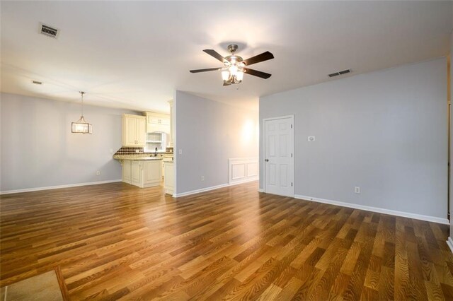 unfurnished living room featuring ceiling fan and dark hardwood / wood-style flooring