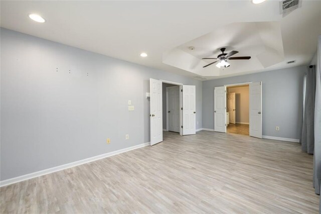 unfurnished room featuring light hardwood / wood-style floors, a raised ceiling, and ceiling fan