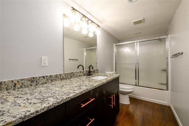 full bathroom with wood-type flooring, vanity, toilet, and combined bath / shower with glass door