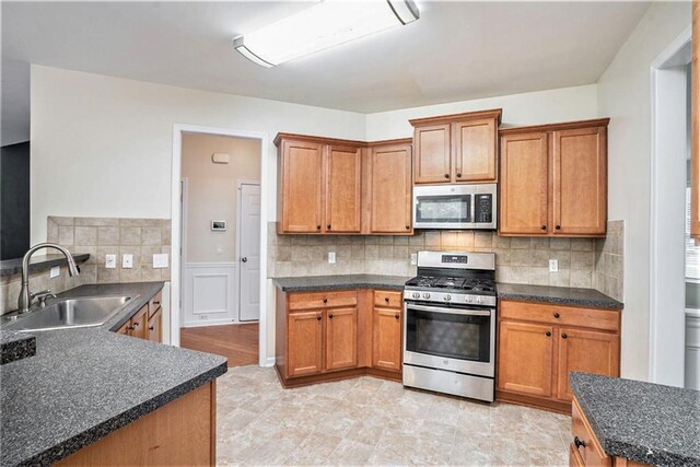 157 Spur Ln, Hiram, GA 30141 - kitchen featuring appliances with stainless steel finishes, a sink, dark countertops, and brown cabinetry
