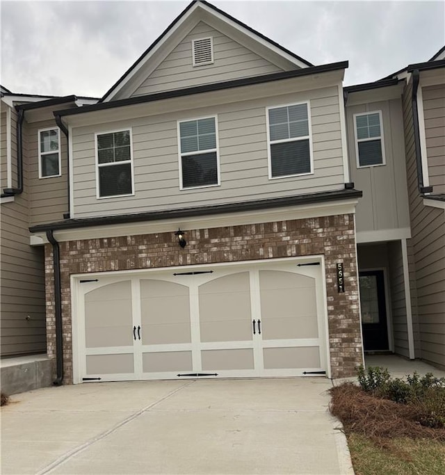 townhome / multi-family property featuring brick siding, a garage, and concrete driveway