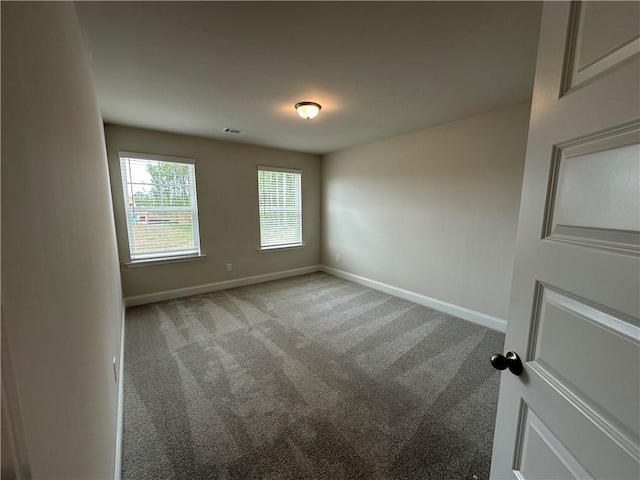 empty room with carpet floors, baseboards, and visible vents