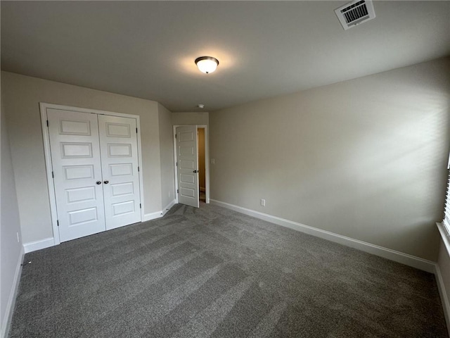 unfurnished bedroom featuring a closet, baseboards, visible vents, and dark colored carpet