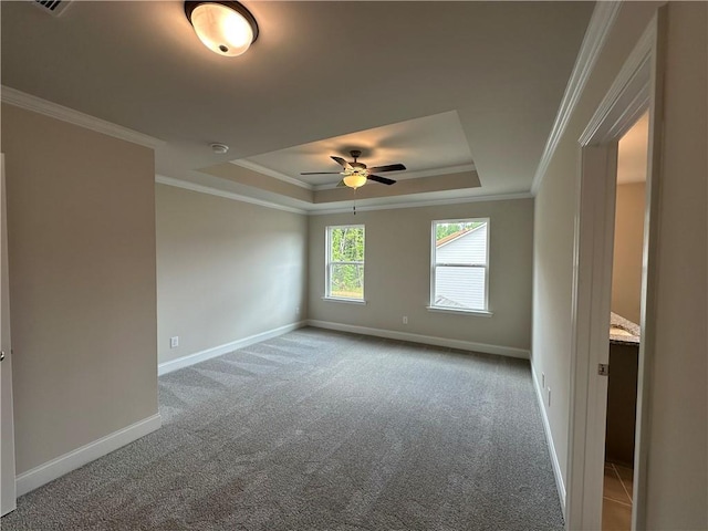 carpeted empty room with baseboards, a ceiling fan, crown molding, and a tray ceiling