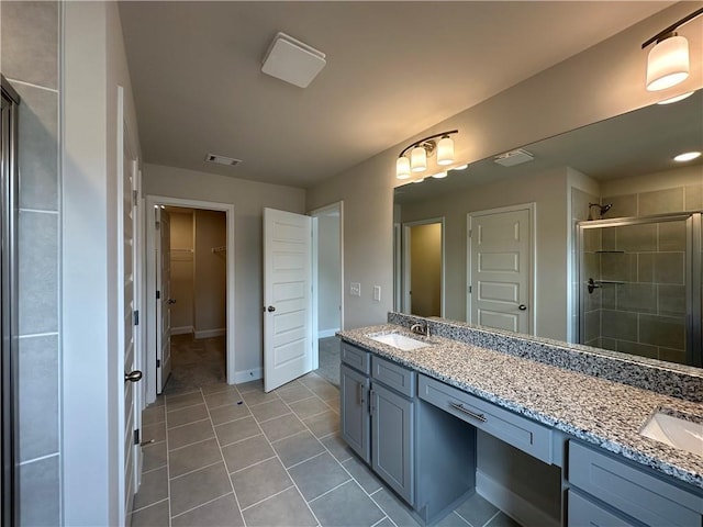 bathroom with a sink, tile patterned flooring, double vanity, visible vents, and a stall shower