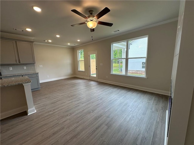 unfurnished living room with visible vents, ornamental molding, and baseboards