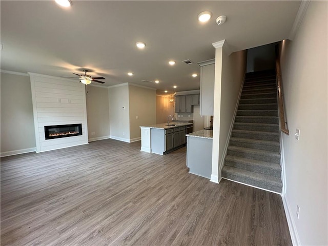 unfurnished living room with crown molding, baseboards, and ceiling fan