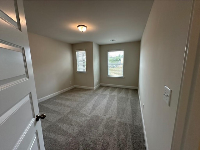spare room with baseboards, light colored carpet, and visible vents