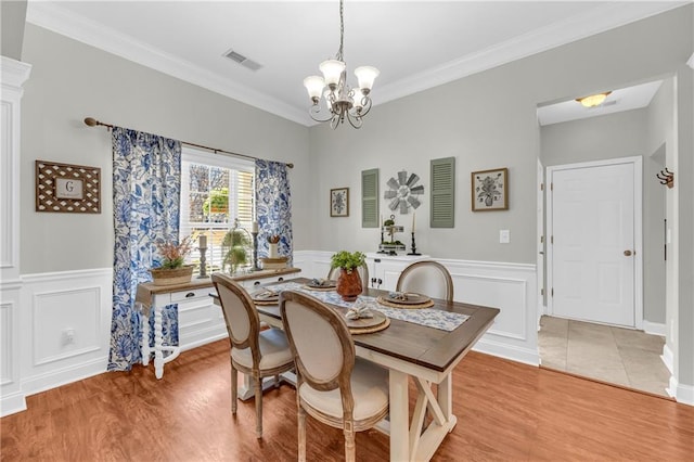 dining area with light wood-type flooring, visible vents, a chandelier, and ornamental molding