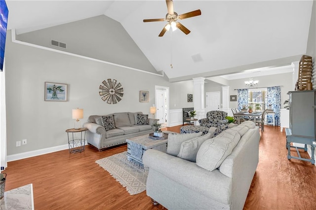 living area with wood finished floors, visible vents, ornate columns, high vaulted ceiling, and ceiling fan with notable chandelier